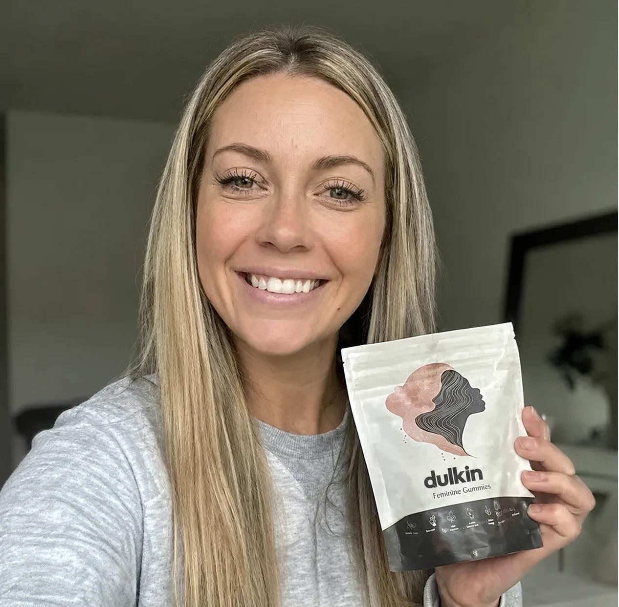 Existing Dulkin lifestyle photo of a woman holding the feminine gummies pouch